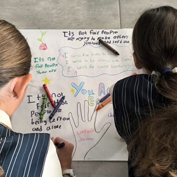 Two children writing and drawing on paper